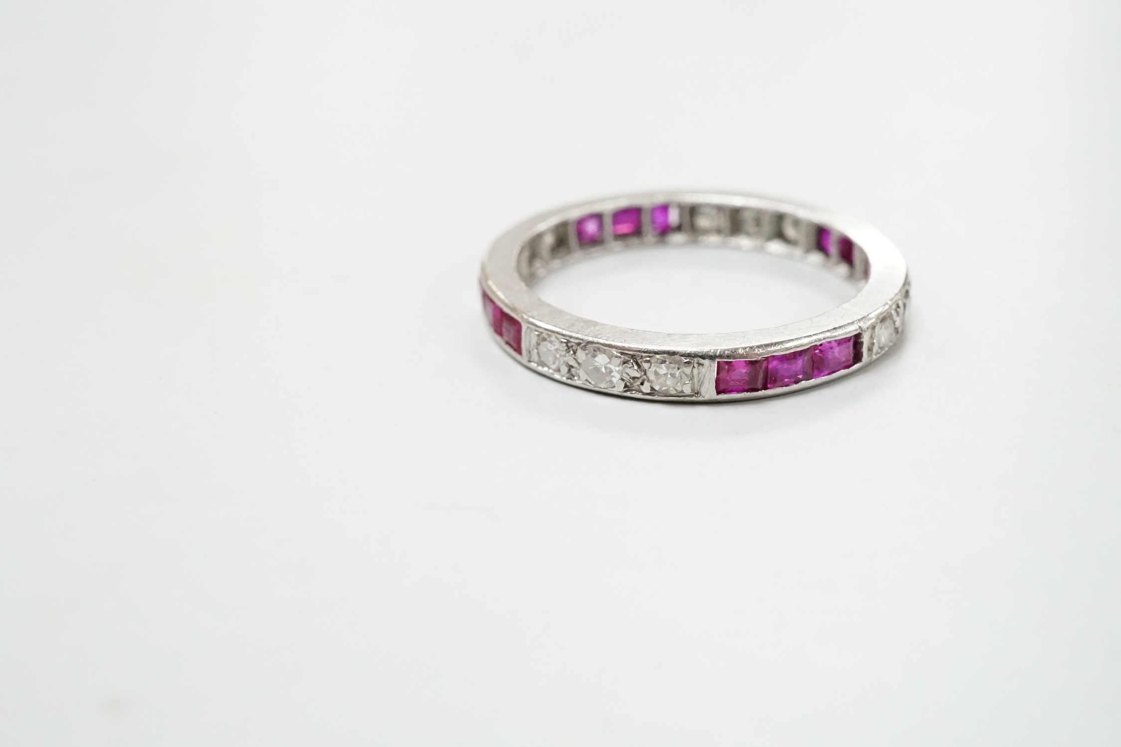 A white metal, ruby and diamond set full eternity ring, size L/M, gross weight 3.1 grams.